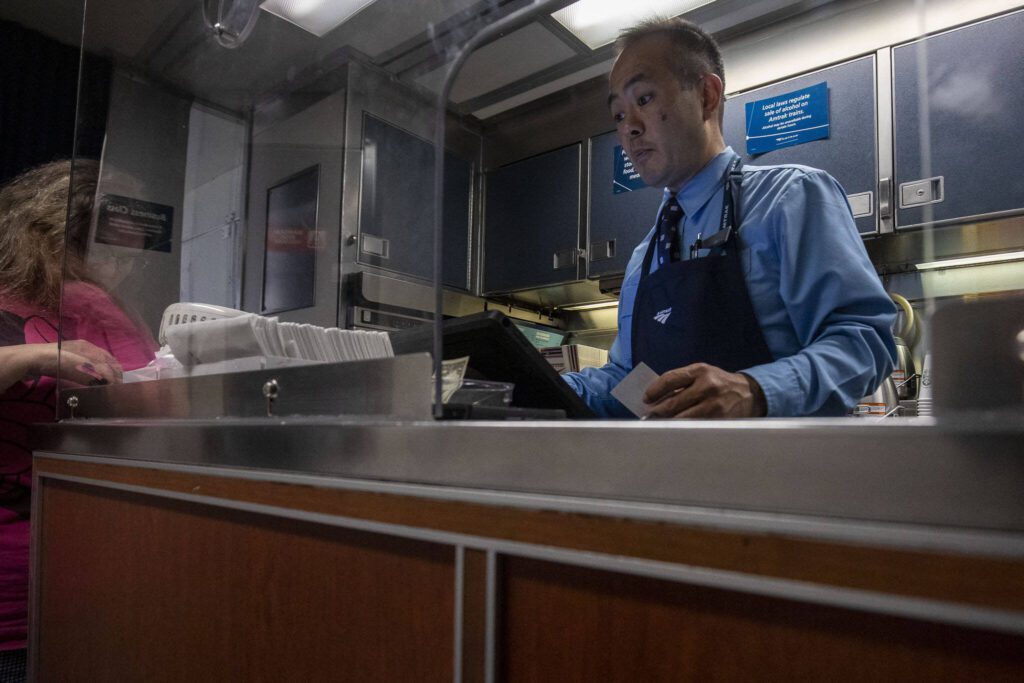 Amtrak worker Darryl Sumida rings up a transaction in the cafe car. (Annie Barker / The Herald)
