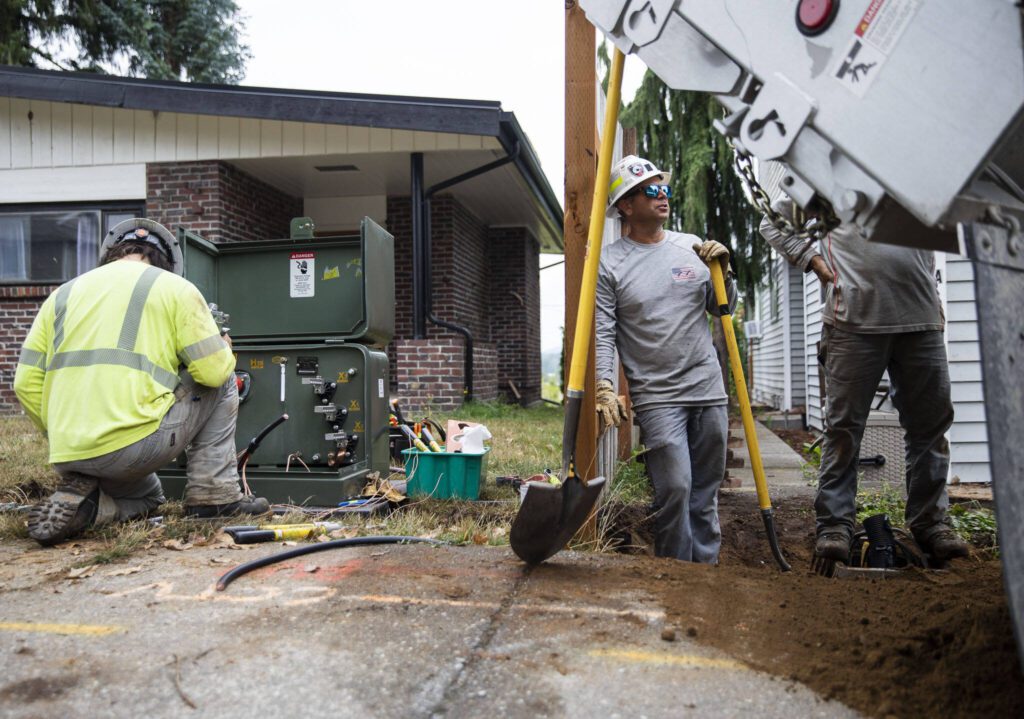 Nic Belisle right, helps shovel dirt to cover up a new underground power line on Thursday, Aug. 31, 2023 in Arlington, Washington. (Olivia Vanni / The Herald)
