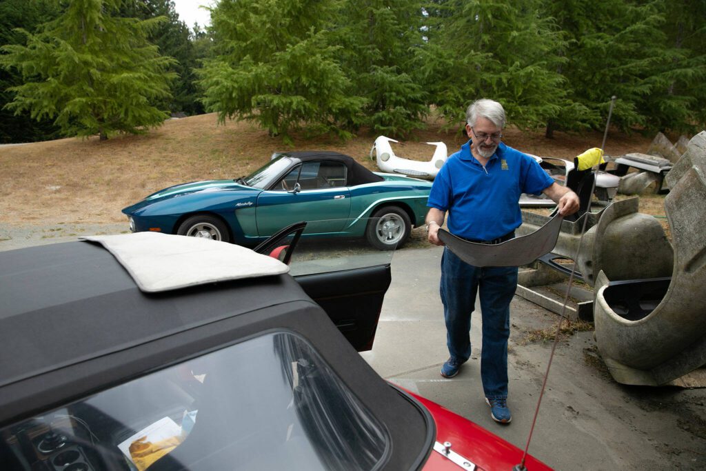 Jim Simpson moves some floor mats back into his Miami Roadster on Friday, August 25, 2023, in Clinton, Washington. Simpson’s Miami Roadster, like quite a few of his designs, is derived from a Mazda Miata. (Ryan Berry / The Herald)
