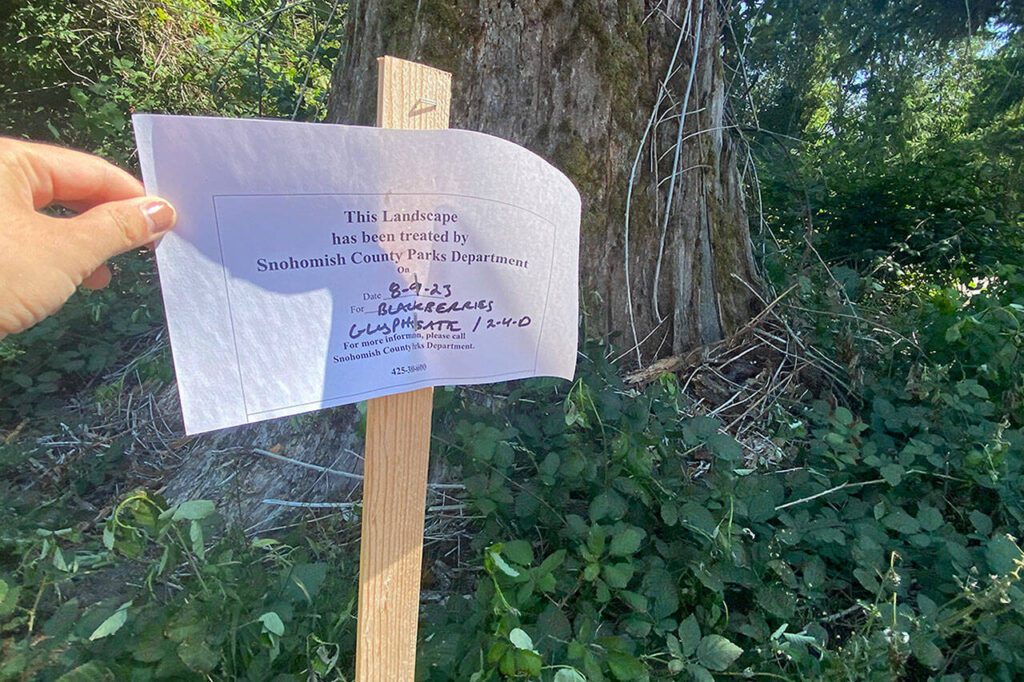 A sign explains the nearby area was sprayed with glyphosate and 2,4-D on Aug. 9, 2023. (Ta’Leah Van Sistine / The Herald)
