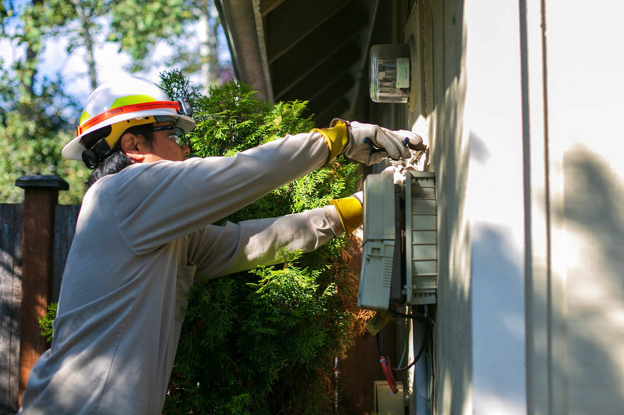 PUD Meter Journeyman Evan Aratani removes a meter reader from the 1960’s before installing a new smart reader at a single family home Thursday, Sept. 21, 2023, in Mill Creek, Washington. (Ryan Berry / The Herald)