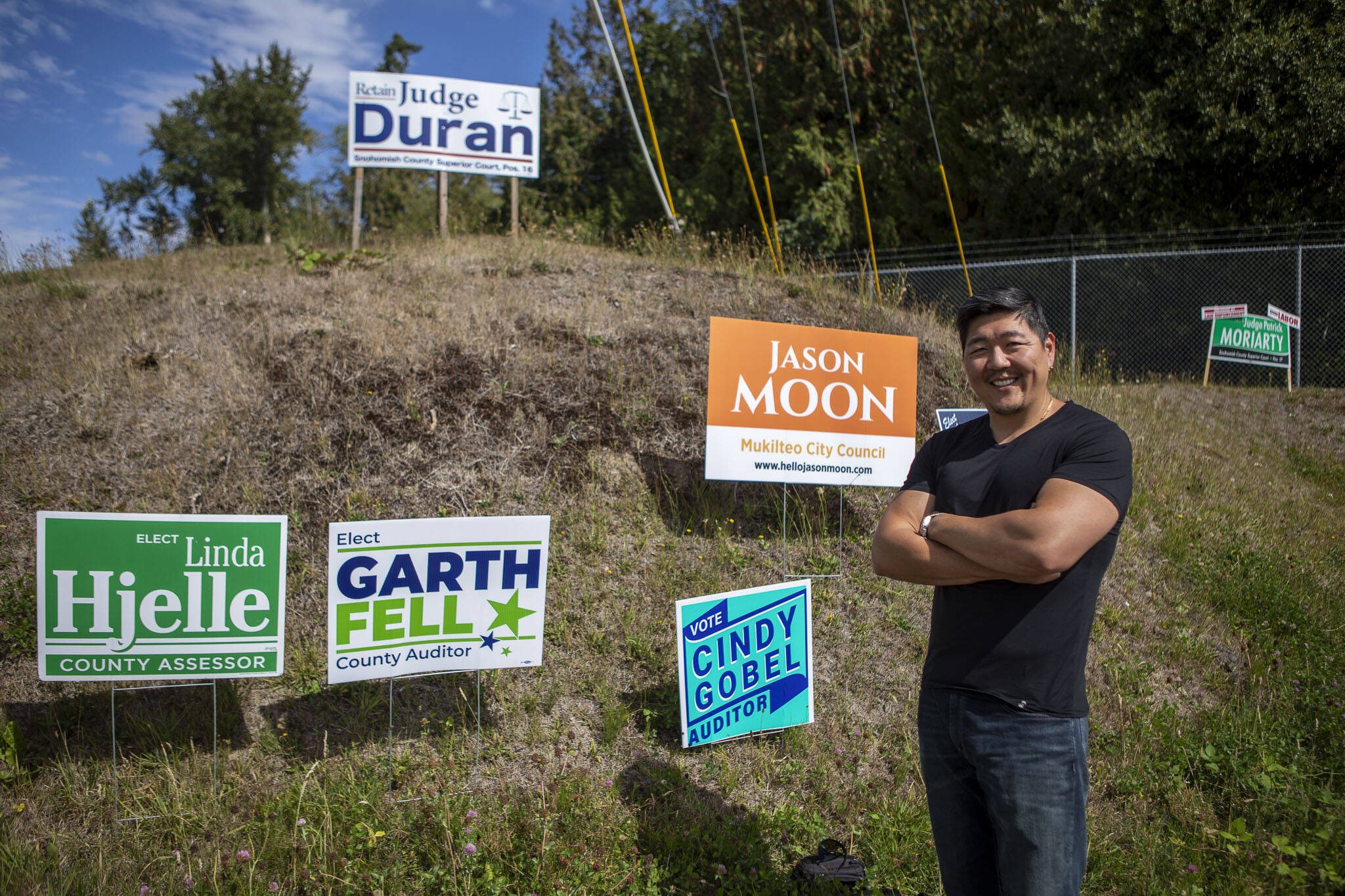 Mukilteo City Council member Jason Moon poses for a photo with his campaign sign along Mukilteo Speedway in Mukilteo, Washington, on Thursday, Sept. 7, 2023. (Annie Barker / The Herald)