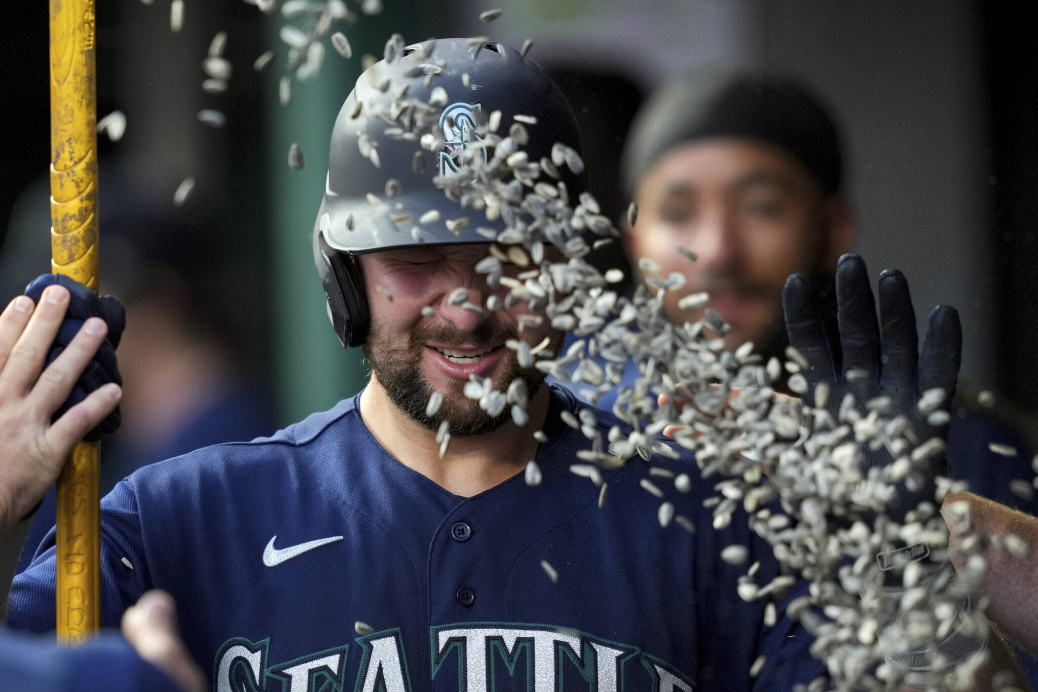 The Mariners’ Cal Raleigh is pelted with sunflower seeds in the dugout after hitting a solo home run during the fourth inning of a game against the Reds on Wednesday in Cincinnati. (AP Photo/Aaron Doster)