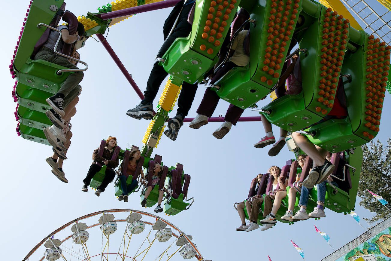 Thrill-seekers fly through the air on a ride during opening day of the Evergreen State Fair on Thursday, August 24, 2023, in Monroe, Washington. (Ryan Berry / The Herald)