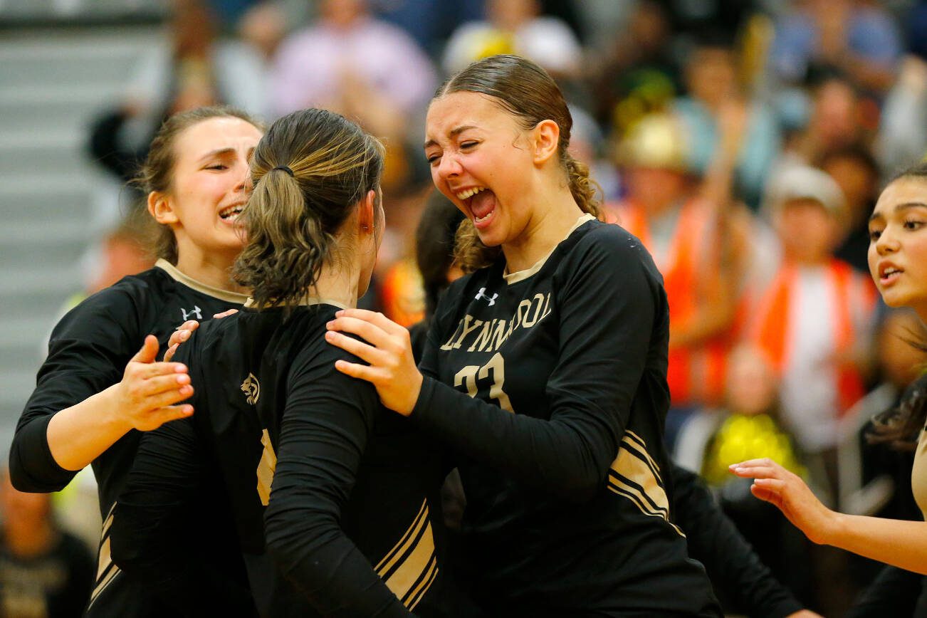 Lynnwood teammates mob senior Abbie Orr (4) after her impressive dig led to a point against Jackson during a volleyball match Thursday, Sept. 14, 2023, at Lynnwood High School in Bothell, Washington. (Ryan Berry / The Herald)