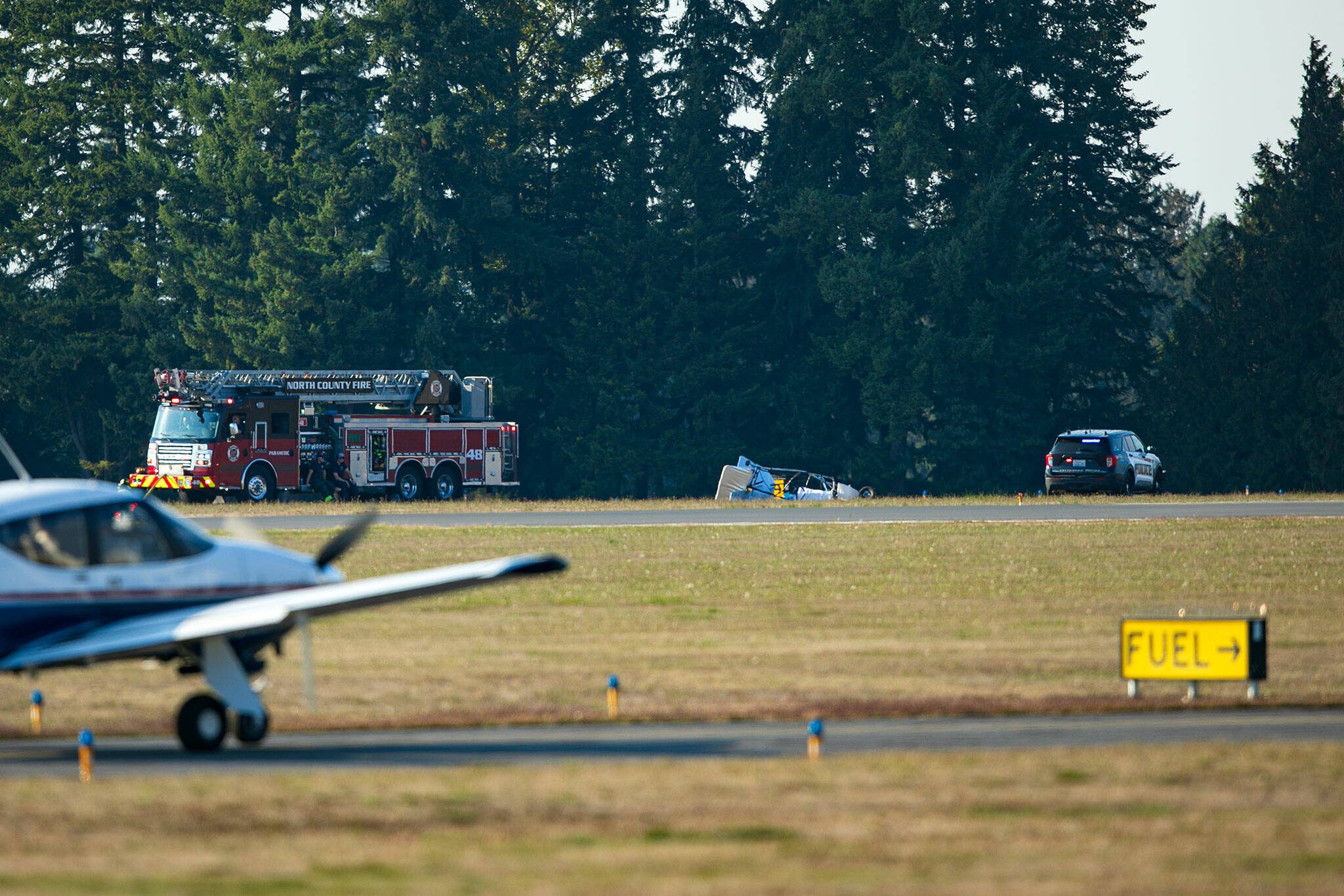 Emergency responders surround an ultralight airplane that crashed Friday, Sept. 22, 2023, at the Arlington Municipal Airport in Arlington, Washington, resulting in the pilot’s death. (Ryan Berry / The Herald)