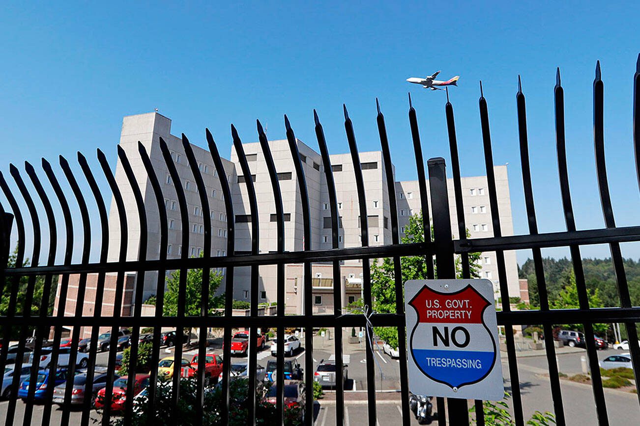 The Federal Detention Center where Blanca Orantes-Lopez is held some 3,000 miles away from her child is seen behind a fence as a jet flies overhead Tuesday, June 19, 2018, in SeaTac, Wash. The woman from El Salvador sits in the federal prison south of Seattle, having reported to immigration authorities after crossing the U.S.-Mexico border illegally in Texas. Her son, Abel Alexander, is in the government's custody at a children's home in Kingston, New York. She has no idea when she might see her child, one of about 2,000 children President Donald Trump's administration has taken from their parents as it cracks down on illegal immigration. (AP Photo/Elaine Thompson)