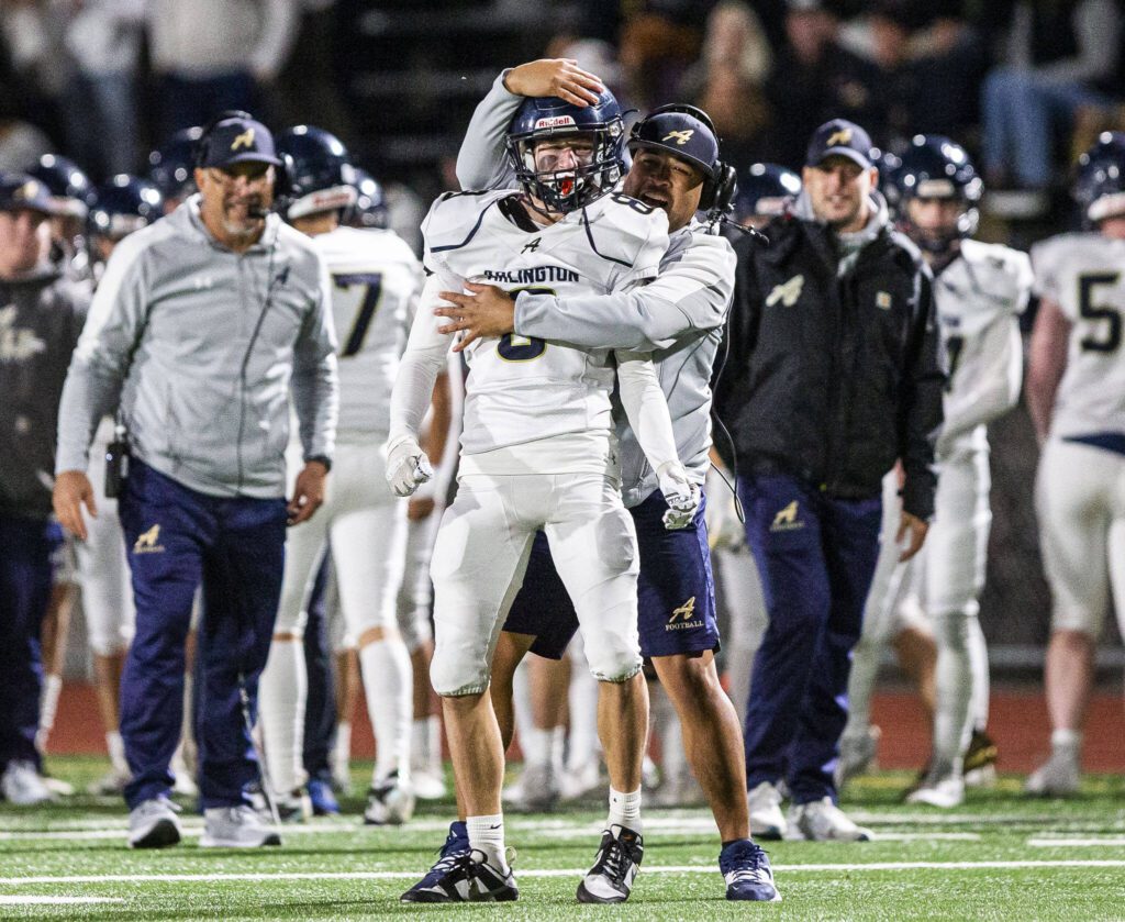 Arlington’s Kaid Hunter is hugged by one of his coaches during the game against Stanwood on Friday, Sept. 29, 2023 in Stanwood, Washington. (Olivia Vanni / The Herald)
