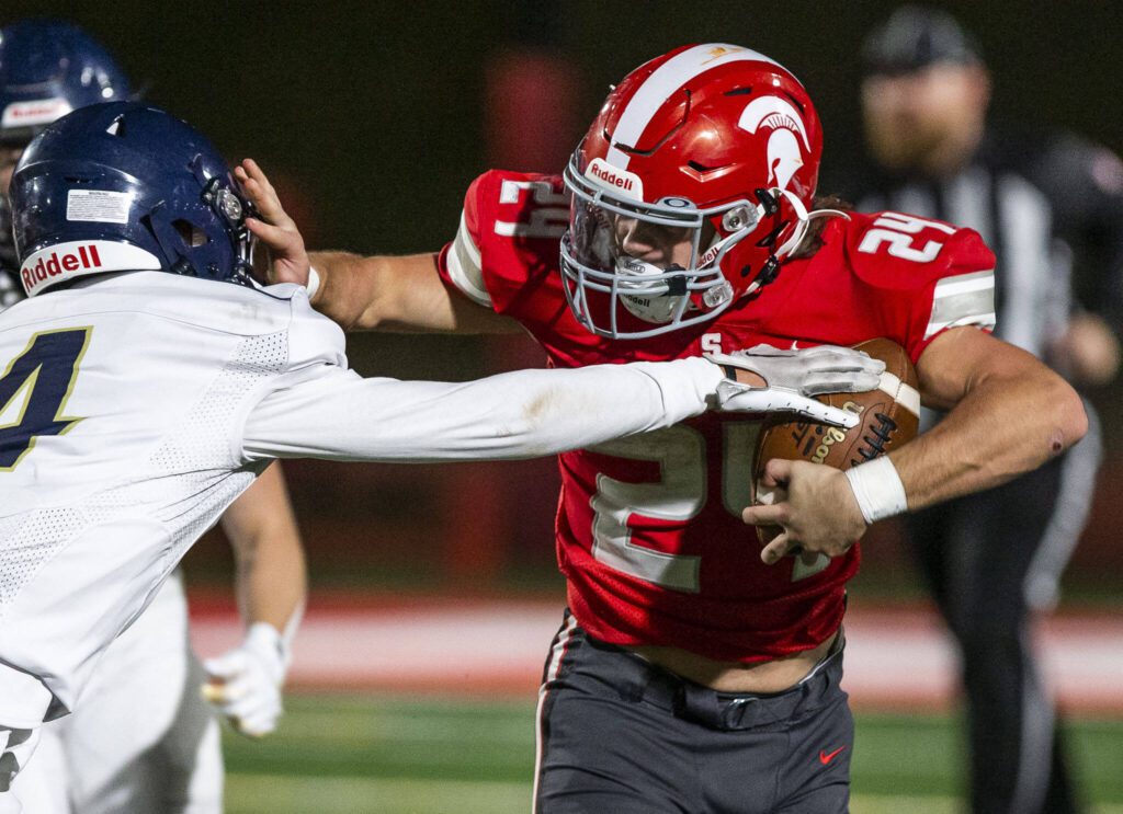 Stanwood’s Cruise Swanson pushes Arlington’s Jake Willis away while he runs the ball during the game on Friday, Sept. 29, 2023 in Stanwood, Washington. (Olivia Vanni / The Herald)
