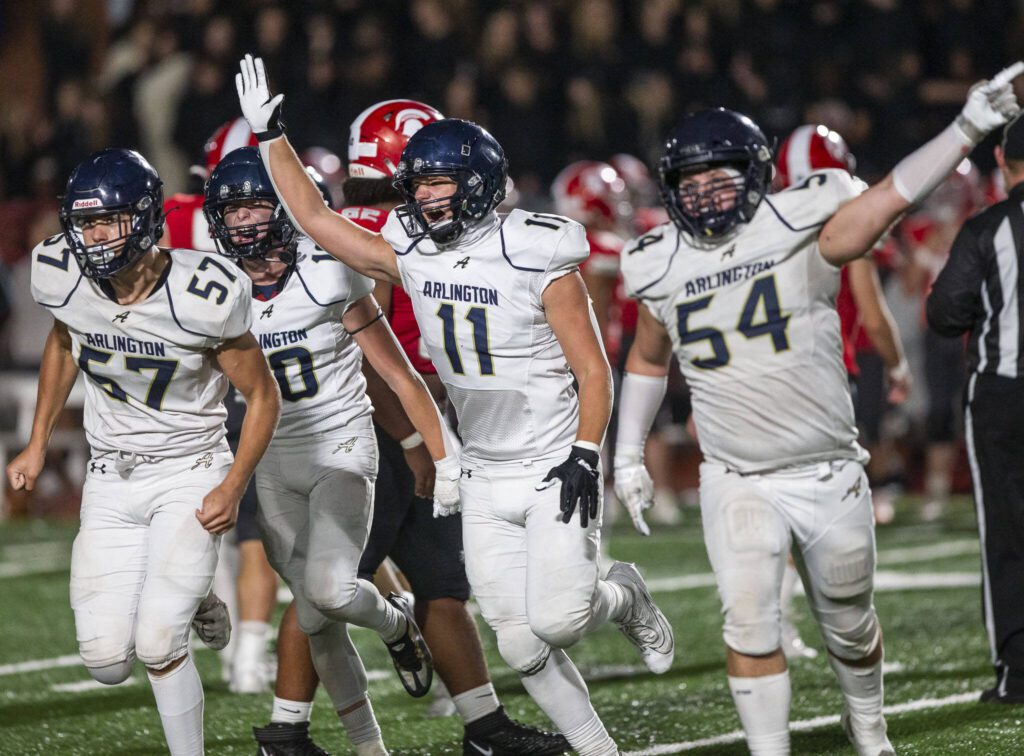 Arlington players react to forcing another turnover during the game against Stanwood on Friday, Sept. 29, 2023 in Stanwood, Washington. (Olivia Vanni / The Herald)
