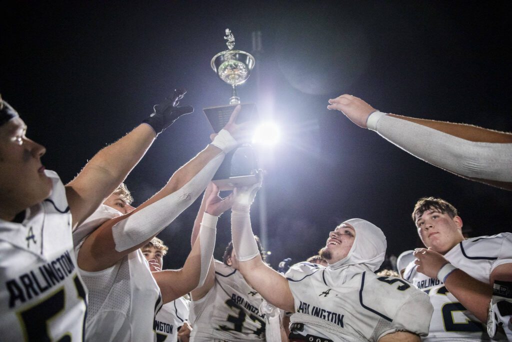 Arlington players lift the Stilly Cup in the air after beating Stanwood on Friday, Sept. 29, 2023 in Stanwood, Washington. (Olivia Vanni / The Herald)
