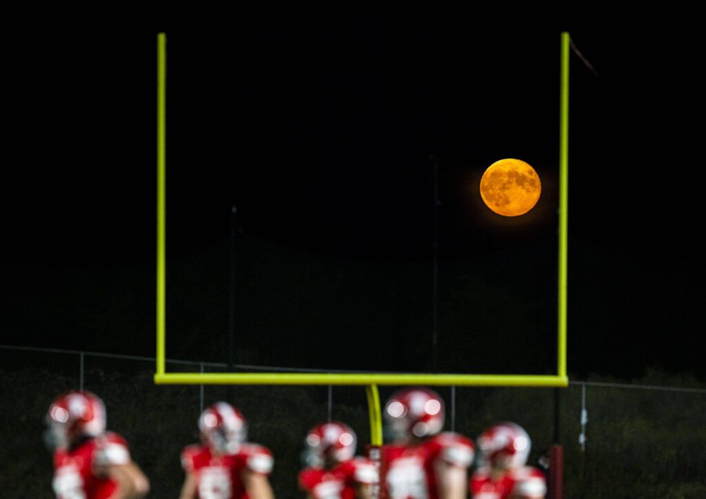 The moon is visible between goalposts at Stanwood’s football field during the game on Friday, Sept. 29, 2023 in Stanwood, Washington. (Olivia Vanni / The Herald)
