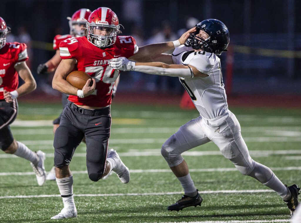 Stanwood’s Cruise Swanson pushes Arlington’s Caiden Patterson away while running the ball during the game on Friday, Sept. 29, 2023 in Stanwood, Washington. (Olivia Vanni / The Herald)
