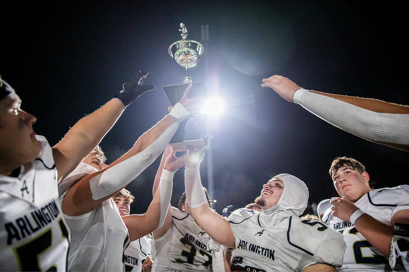 Arlington players lift the Stilly Cup in the air after beating Stanwood on Friday, Sept. 29, 2023 in Stanwood, Washington. (Olivia Vanni / The Herald)