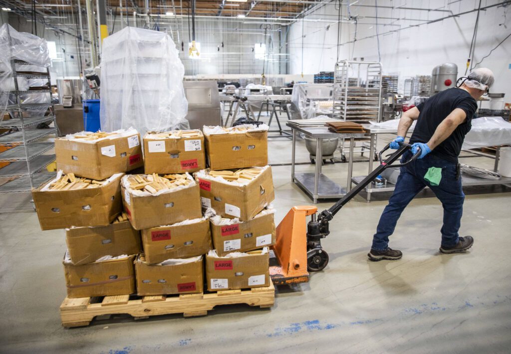 An employee moves multiple boxes of yak cheese chews at Himalayan Dog Chew on Thursday, Sept. 21, 2023 in Arlington, Washington. (Olivia Vanni / The Herald)
