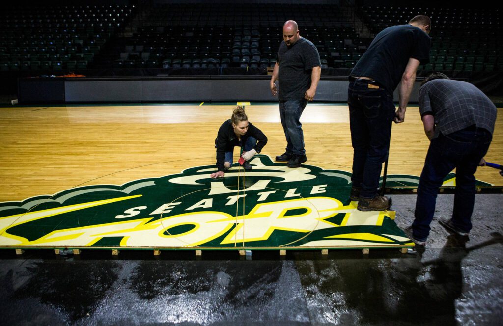 Danielle Pierce, left, and Zach Henricks, right, check to see if there is any spacing between the floor boards during the installation of the Seattle Storm’s floor at Angel of the Winds Arena on Monday, May 13, 2019 in Everett, Washington. (Olivia Vanni / The Herald) 
