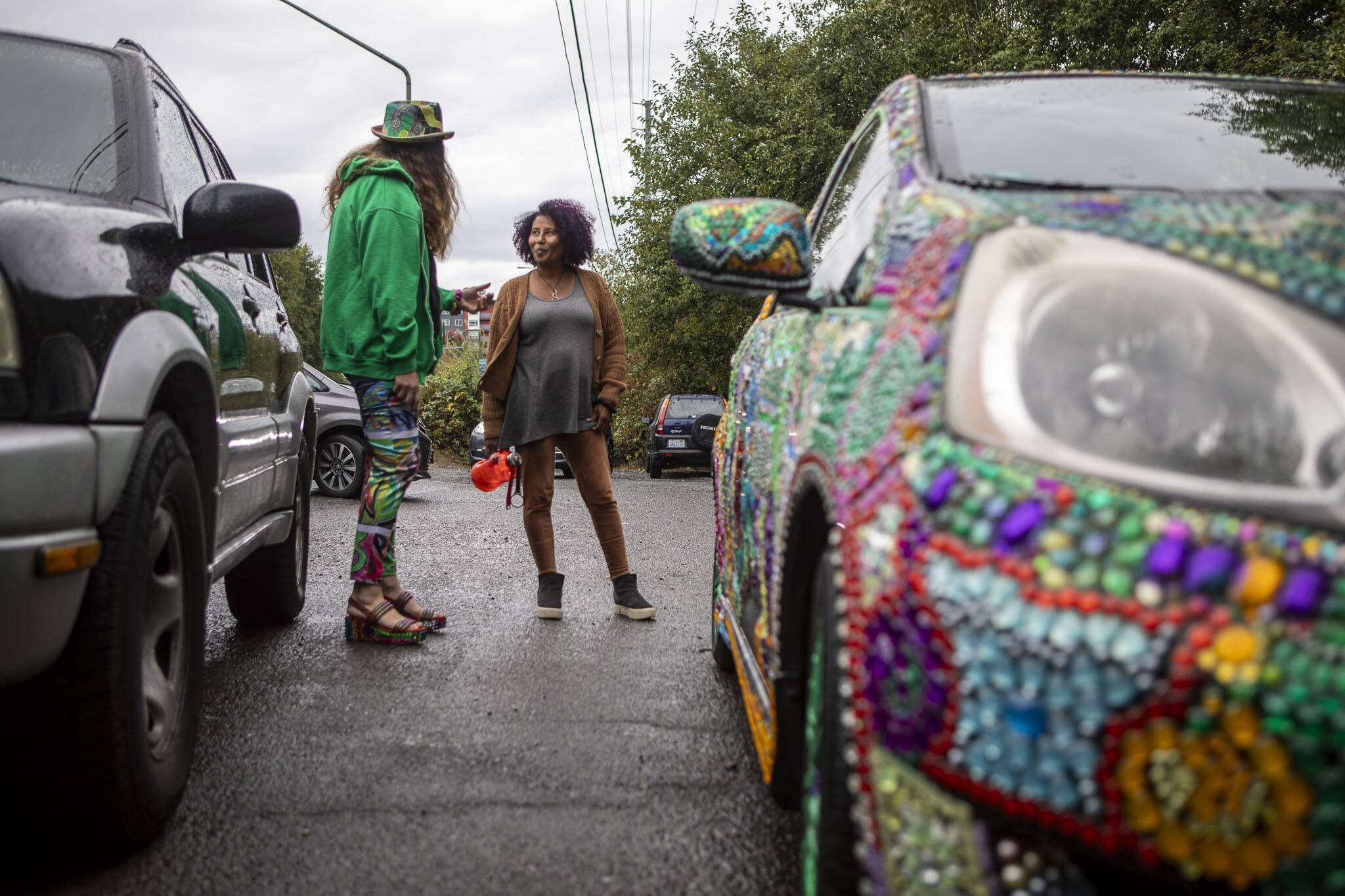 Shannon Kringen, left, talks to Salamawit Tesfamariam, right, about her jeweled car in the parking lot of Lynnwood’s 164th Street artesian well. (Annie Barker / The Herald)