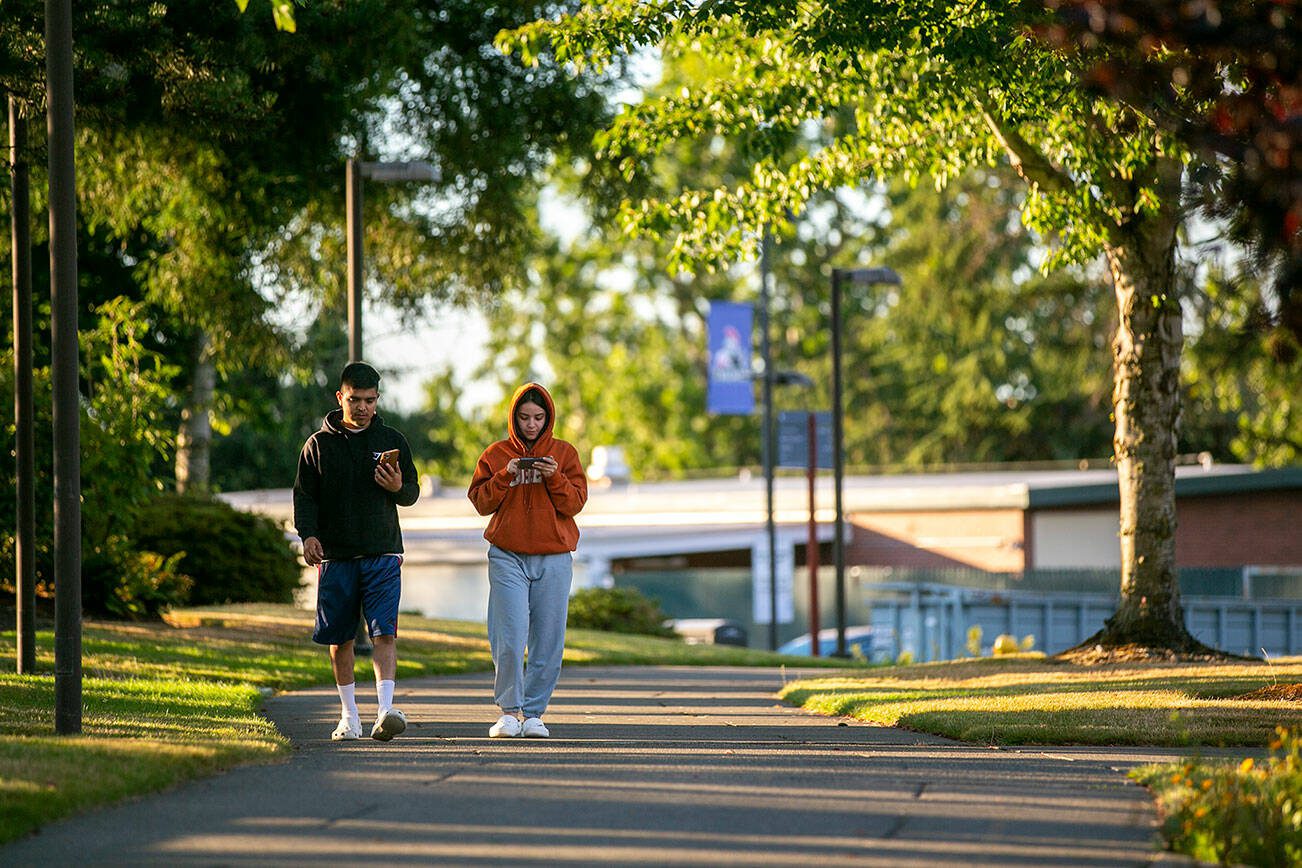 Two students walk along a path through campus Thursday, Aug. 4, 2022, at Everett Community College in Everett, Washington. The college’s youth-reengagement program has lost its funding, and around 150 students are now without the money they need to attend classes. (Ryan Berry / The Herald)