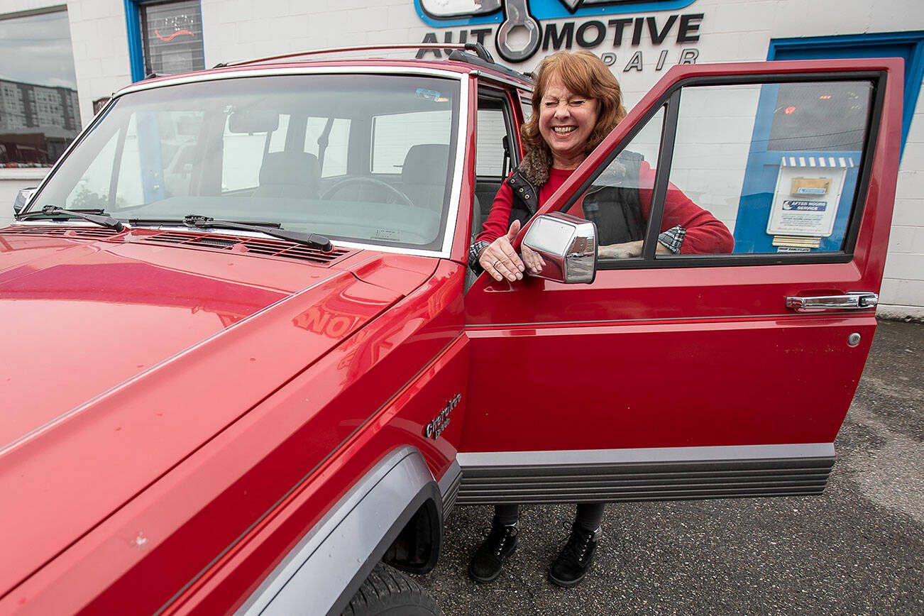 Barb Denton smiles and laughs with her Jeep Cherokee Laredo that she has driven for 32 years on Wednesday, Sept. 27, 2023 in Everett, Washington. (Olivia Vanni / The Herald)