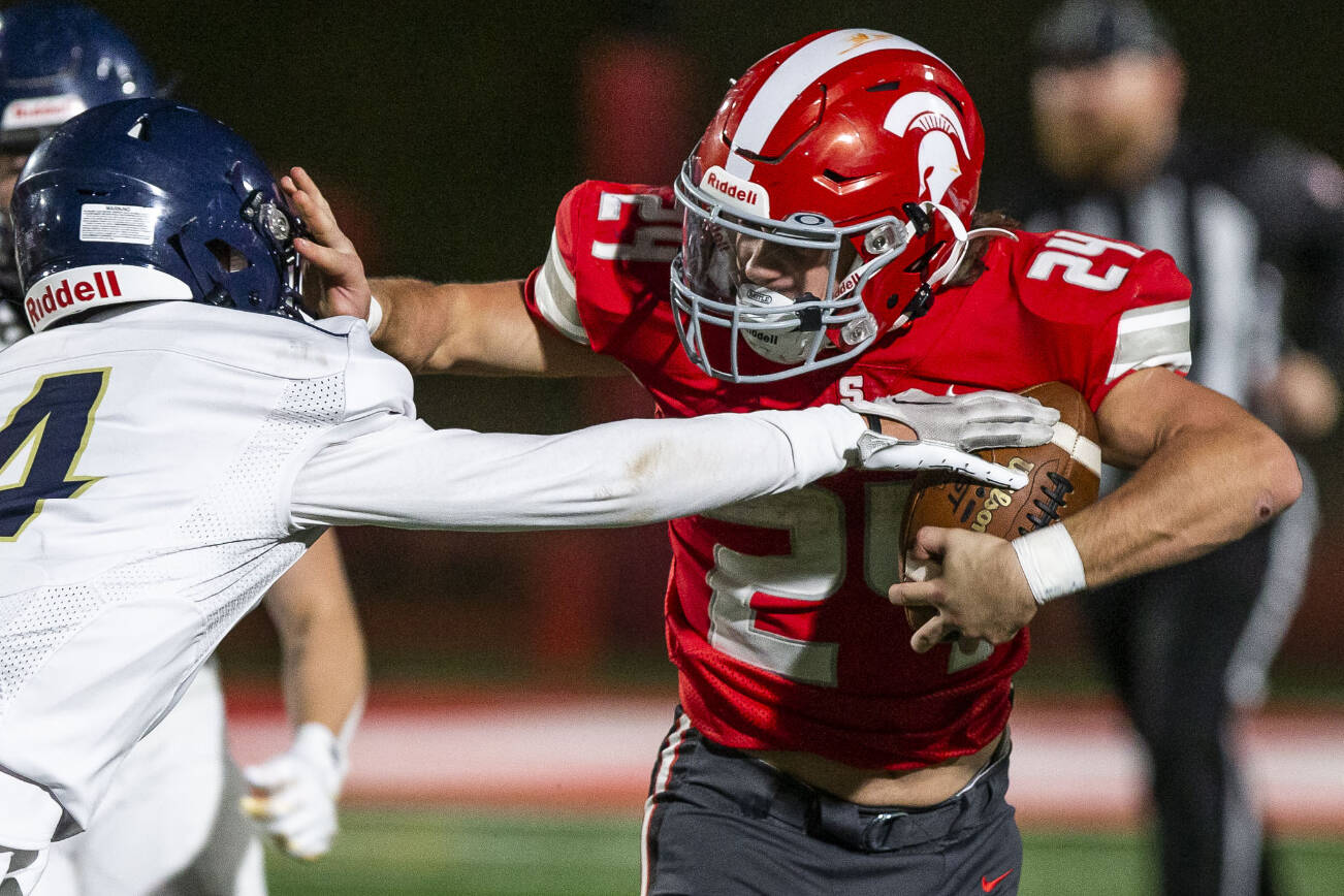 Stanwood's Cruise Swanson pushes Arlington's Jake Willis away while he runs the ball during the game on Friday, Sept. 29, 2023 in Stanwood, Washington. (Olivia Vanni / The Herald)