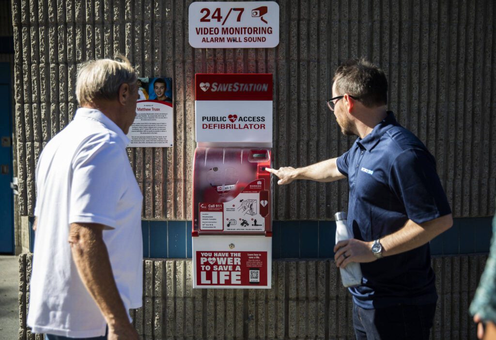 People gather to look at the new AED available for emergency use at the Meadowdale Athletic Complex on Friday, Oct. 6, 2023 in Lynnwood, Washington. (Olivia Vanni / The Herald)
