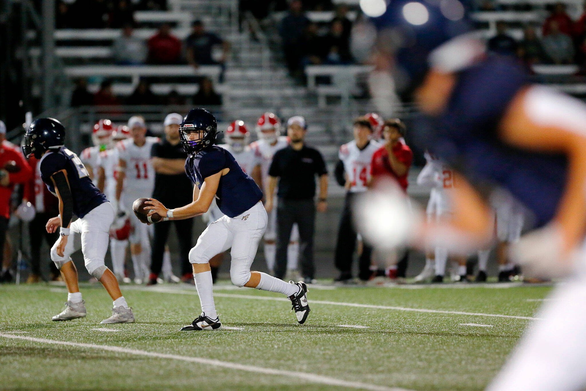 Arlington’s Leyton Martin takes the snap and looks for a receiver against Marysville Pilchuck on Friday, Oct. 6, 2023, at Arlington High School in Arlington, Washington. (Ryan Berry / The Herald)