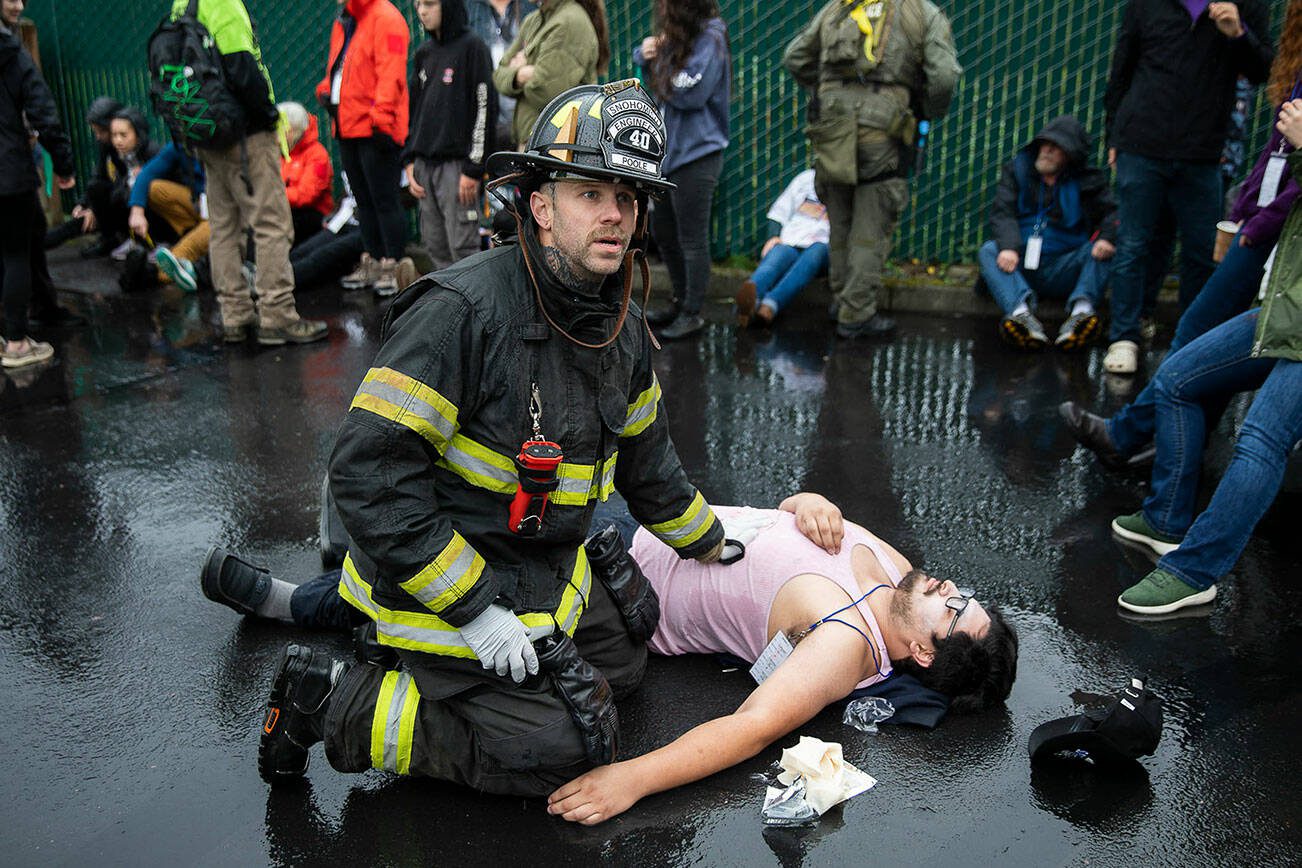 Snohomish firefighter Joshua Poole talks with another firefighter while administering aid to a victim during a mass casualty training on Wednesday, Oct. 11, 2023 in Snohomish, Washington. (Olivia Vanni / The Herald)
