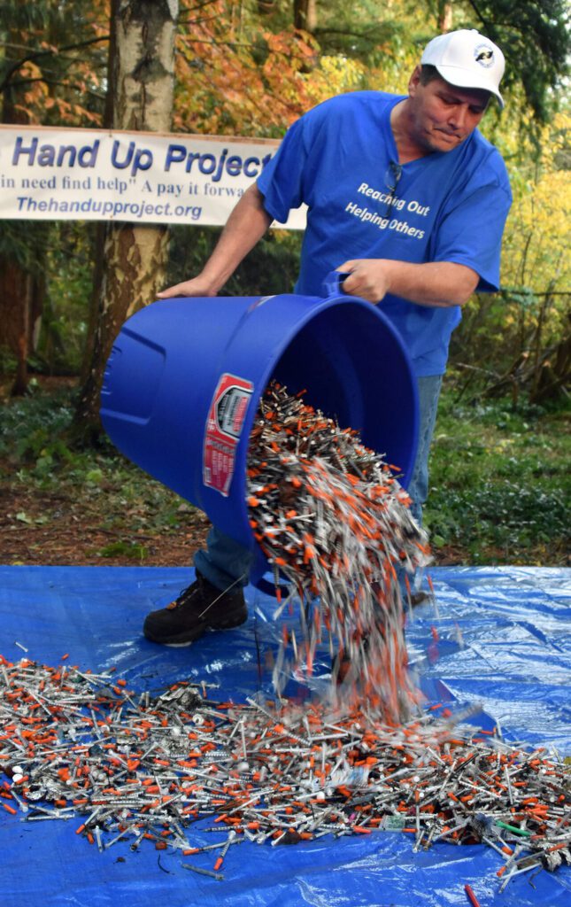 Robert Smiley, the founder of the Hand Up Project, illustrates how many needles were picked up over one weekend at a homeless camp south of Everett in March, 2017. In 2023 the organization ousted Smiley amid an investigation into potential fraud. (Caleb Hutton / The Herald)
