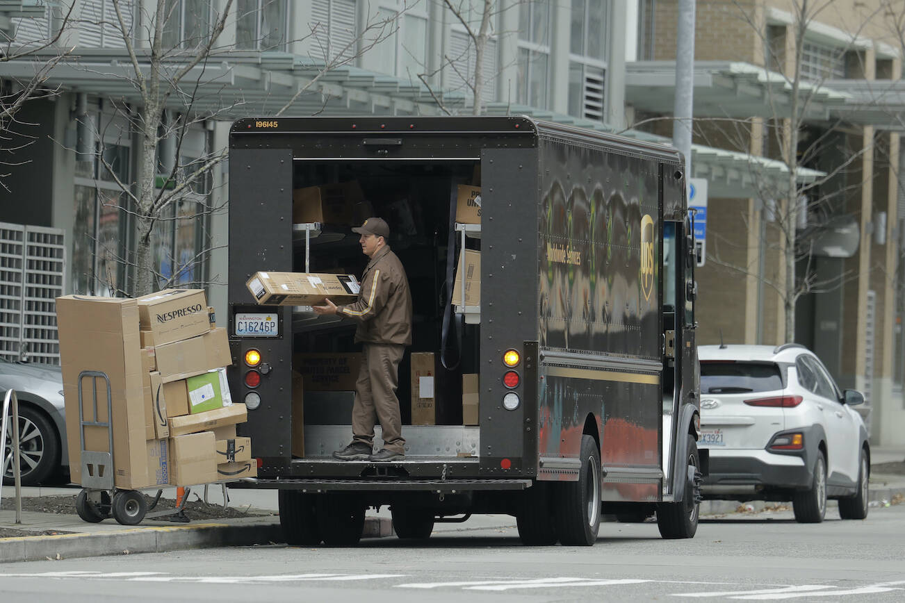 A United Parcel Service driver loads boxes during a delivery, Thursday, March 26, 2020, in downtown Seattle. UPS and other companies have been bush as people staying home under state-wide mandate amidst one of the worst outbreaks of the new coronavirus in the U.S. turn to online shopping to meet their needs. (AP Photo/Ted S. Warren)