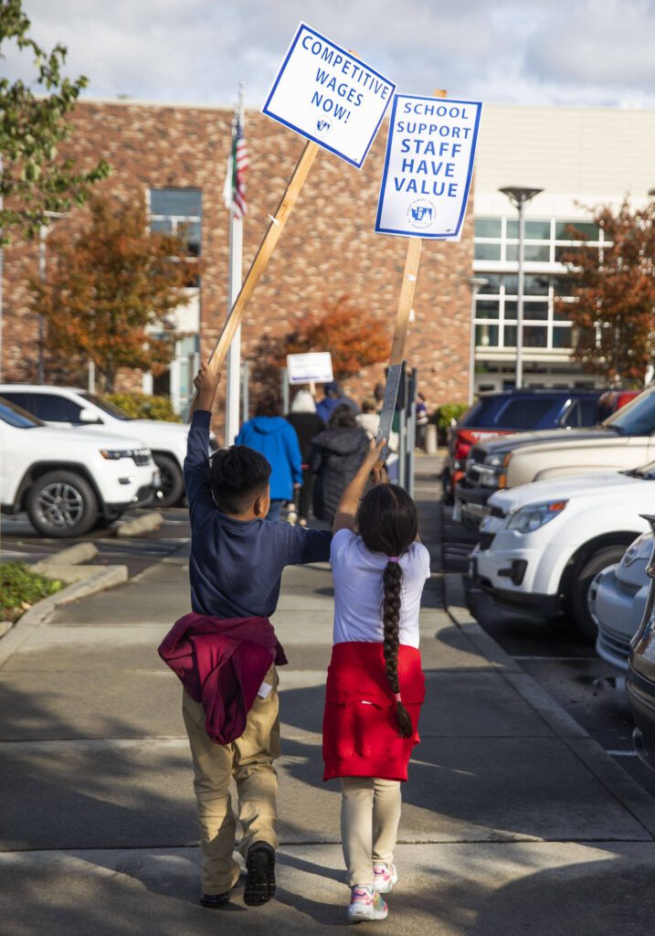 Two children walk toward the Everett Public Schools building to protest with paraeducators on Tuesday, Oct. 10, 2023 in Everett, Washington. (Olivia Vanni / The Herald)

