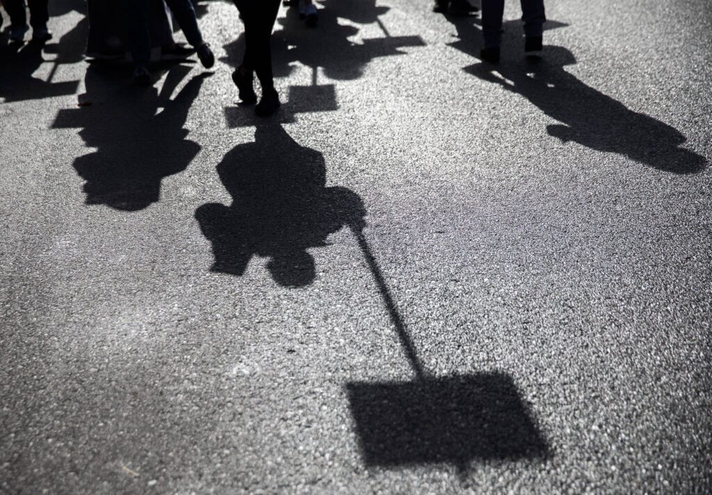 Everett Public Schools paraeducators shadows are cast on the ground as they protest on Tuesday, Oct. 10, 2023 in Everett, Washington. (Olivia Vanni / The Herald)
