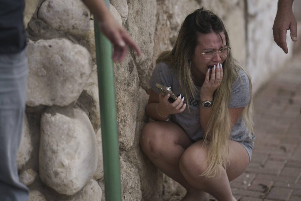 An Israeli woman takes cover from incoming rocket fire from the Gaza Strip, in Ashkelon, southern Israel, Wednesday. (Leo Correa / Associated Press)
