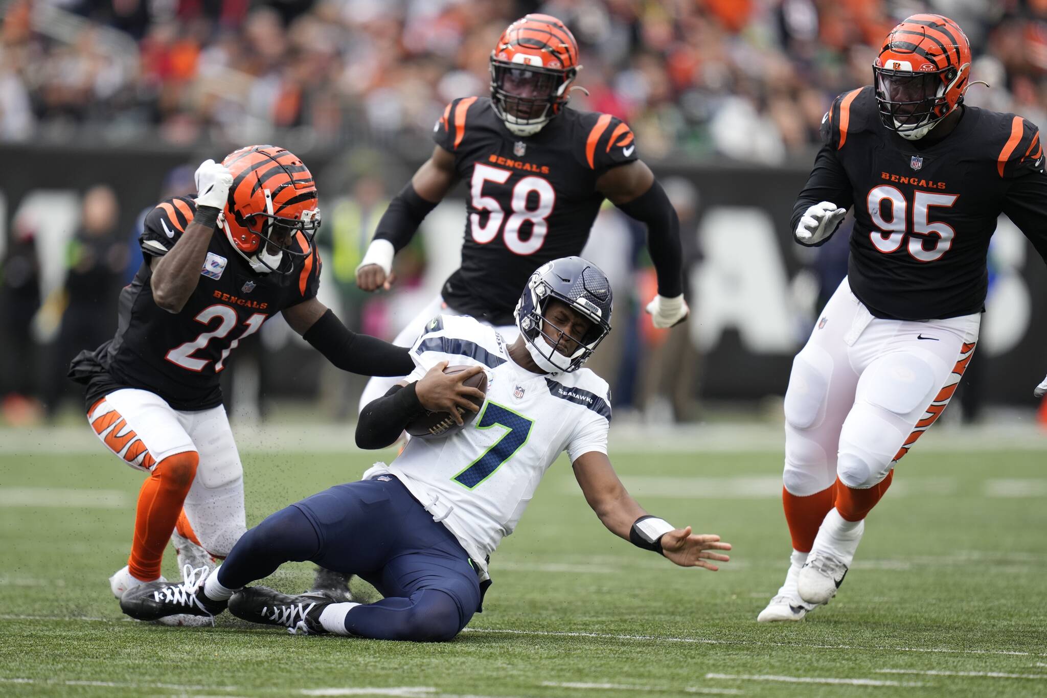 Seattle Seahawks quarterback Geno Smith slides in front of Cincinnati Bengals’ Mike Hilton (21) during the second half of Sunday’s game in Cincinnati. (AP Photo/Michael Conroy)