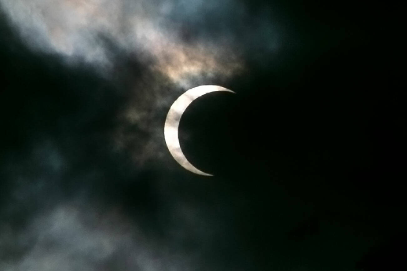 Clouds pass in front of the moon and sun as the two cross paths during an annular eclipse on Saturday, Oct. 14, 2023, seen from Everett, Washington. A total eclipse will be visible over parts of the United States on April 8, 2024. (Ryan Berry / The Herald)