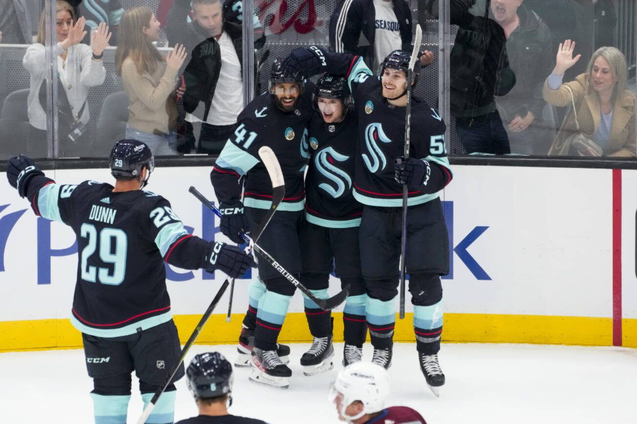 Seattle Kraken right wing Kailer Yamamoto, center, is flanked by left wing Pierre-Edouard Bellemare (41) and left wing Tye Kartye, right, as they celebrate Yamamoto's goal against the Colorado Avalanche during the first period of an NHL hockey game Tuesday, Oct. 17, 2023, in Seattle. (AP Photo/Lindsey Wasson)
