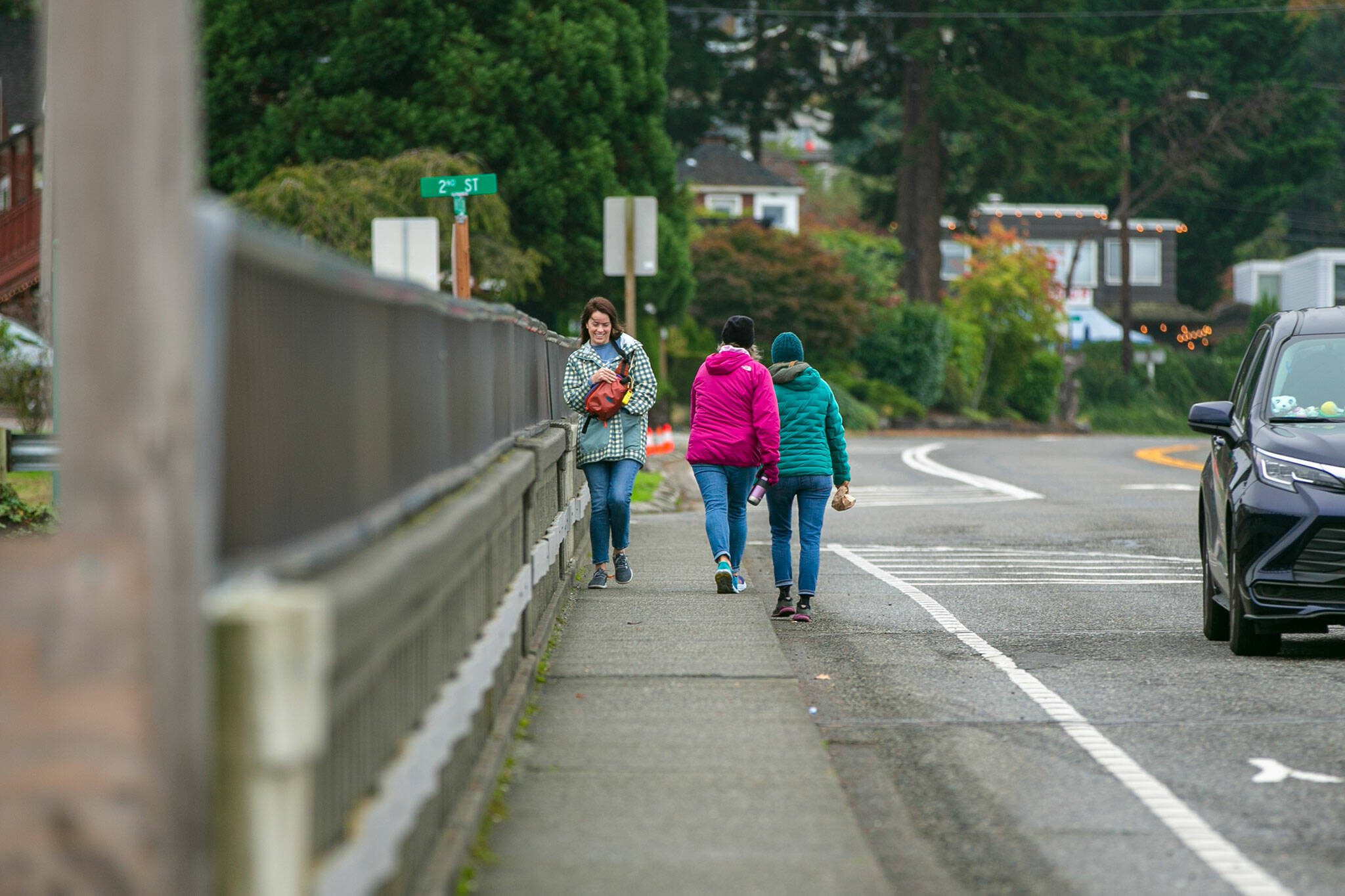 Pedestrians try to make space for each other while passing on the Highway 525 bridge over the train tracks in Mukilteo. (Ryan Berry / The Herald)