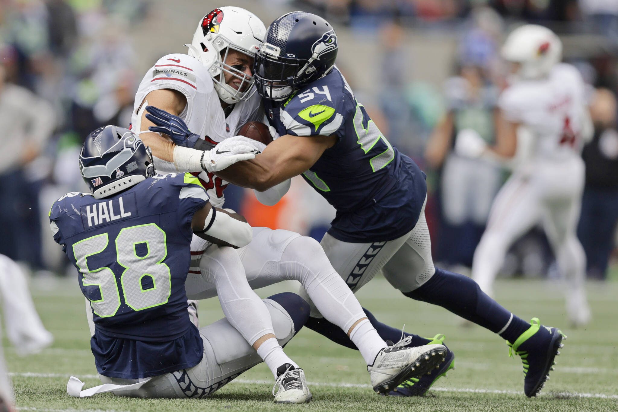 Arizona Cardinals tight end Zach Ertz, center, gets tackled by Seattle Seahawks linebackers Bobby Wagner (54) and Derick Hall (58) during the second half of Sunday’s game in Seattle. (AP Photo/John Froschauer)