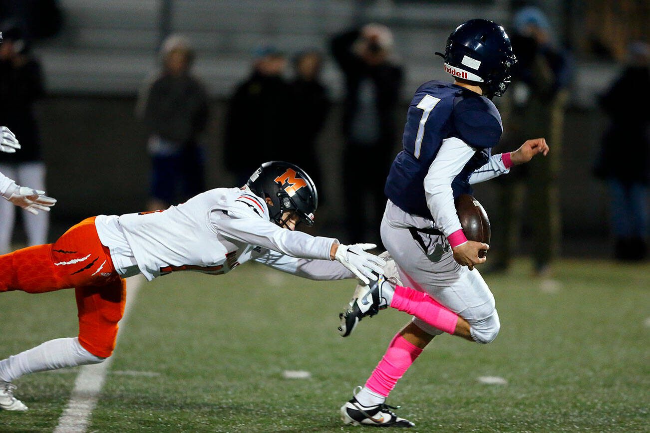 Arlington junior quarterback Leyton Martin slips one last tackle on a long touchdown run against Monroe on Friday, Oct. 27, 2023, at Arlington High School in Arlington, Washington. (Ryan Berry / The Herald)