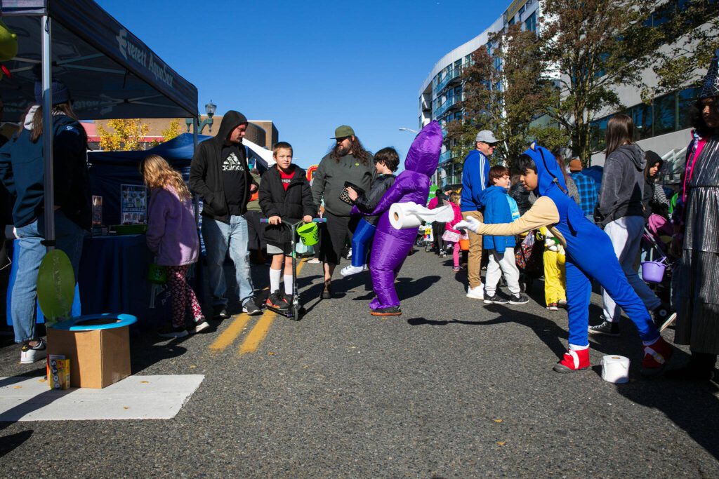 Seven-year-old Raheeb Zaidi, dressed as Sonic the Hedgehog, tosses toilet paper rolls into a toilet at the Everett AquaSox booth during Downtown Everett Association’s trick-or-treat event Saturday, Oct. 28, 2023, in Everett, Washington. Zaidi went 3-for-3 on his tosses. (Ryan Berry / The Herald) 
