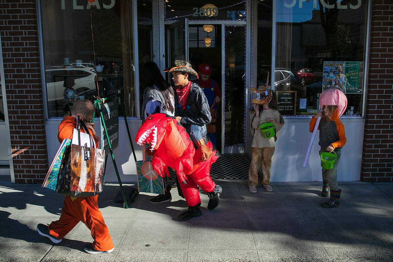 Children, including a cowboy on a dinosaur, come and go from Chai Cupboard as they trick-or-treat up and down Colby during Downtown Everett Association’s Halloween event Saturday, Oct. 28, 2023, in Everett, Washington. (Ryan Berry / The Herald)