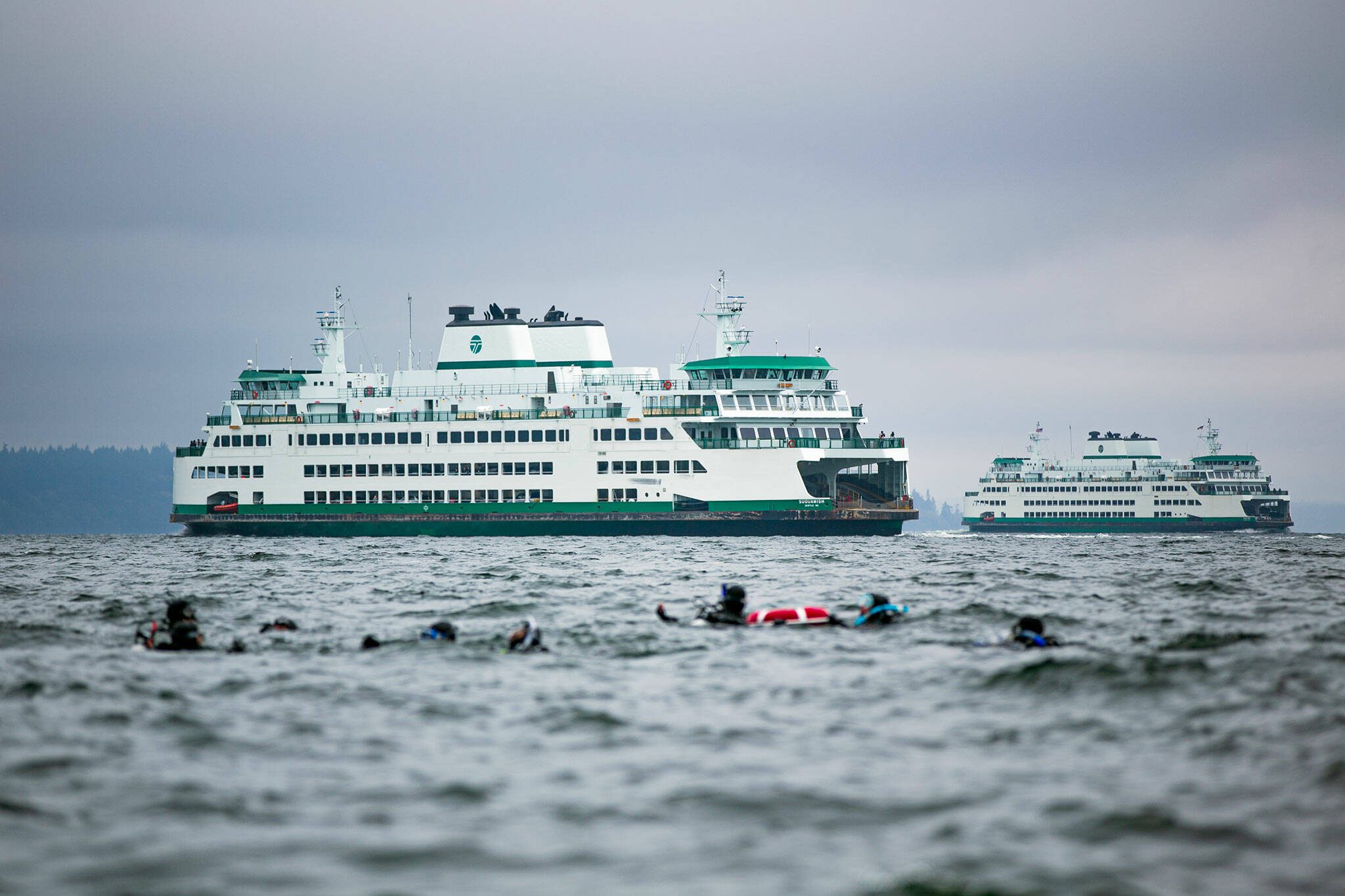 Two Washington State ferries pass along the route between Mukilteo and Clinton as scuba divers swim near the shore Sunday, Oct. 22, 2023, in Mukilteo, Washington. (Ryan Berry / The Herald)