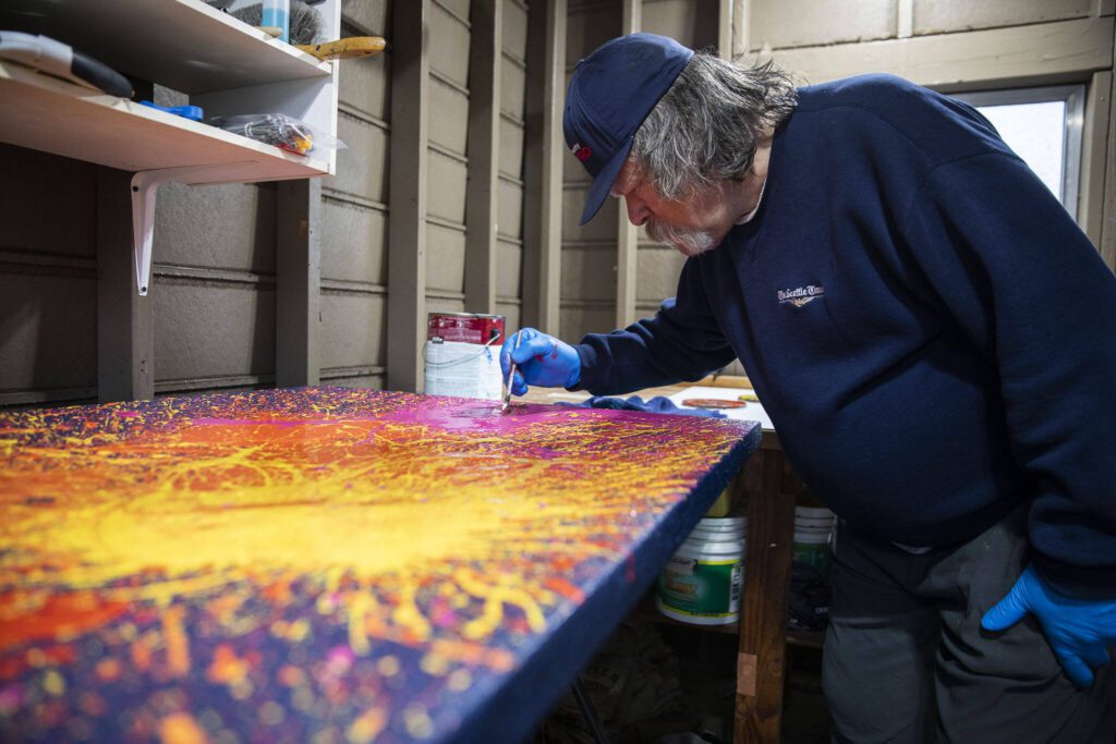 Sam Taylor pops air bubbles in paint while he works on one of his art pieces. (Olivia Vanni / The Herald)
