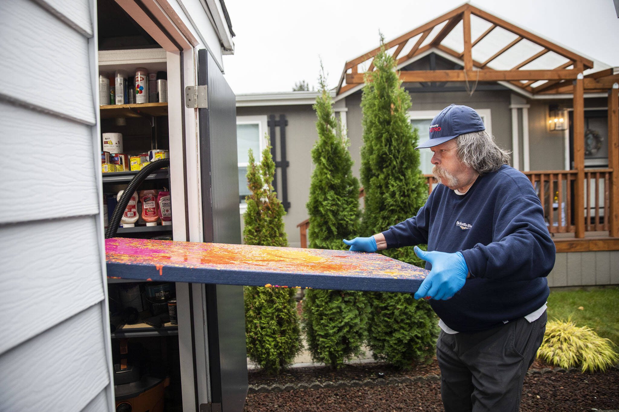 Sam Taylor carries a freshly painted canvas into his home workshop. (Olivia Vanni / The Herald)