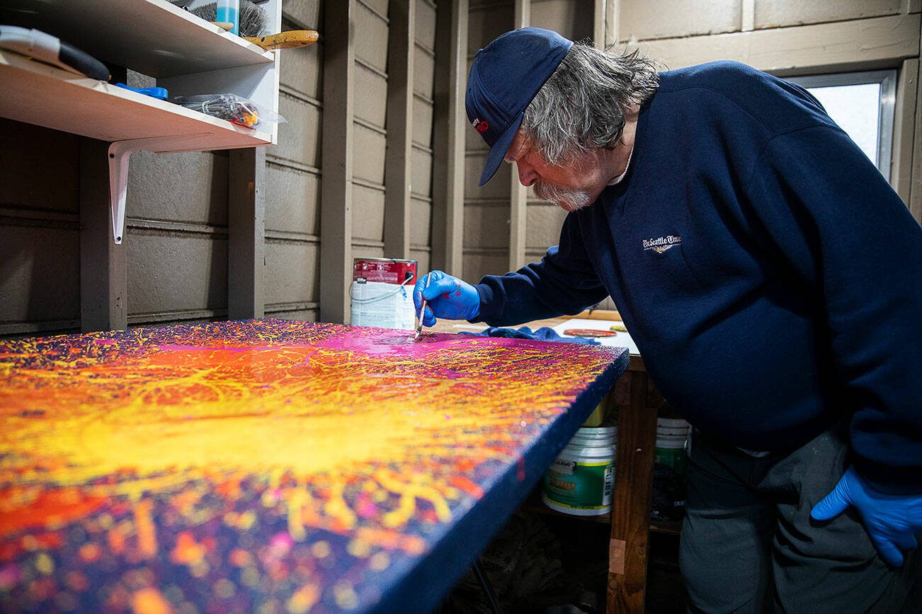 Sam Taylor pops air bubbles in paint while he works on one of his art pieces on Tuesday, Oct. 3, 2023, in Everett, Washington. (Olivia Vanni / The Herald)