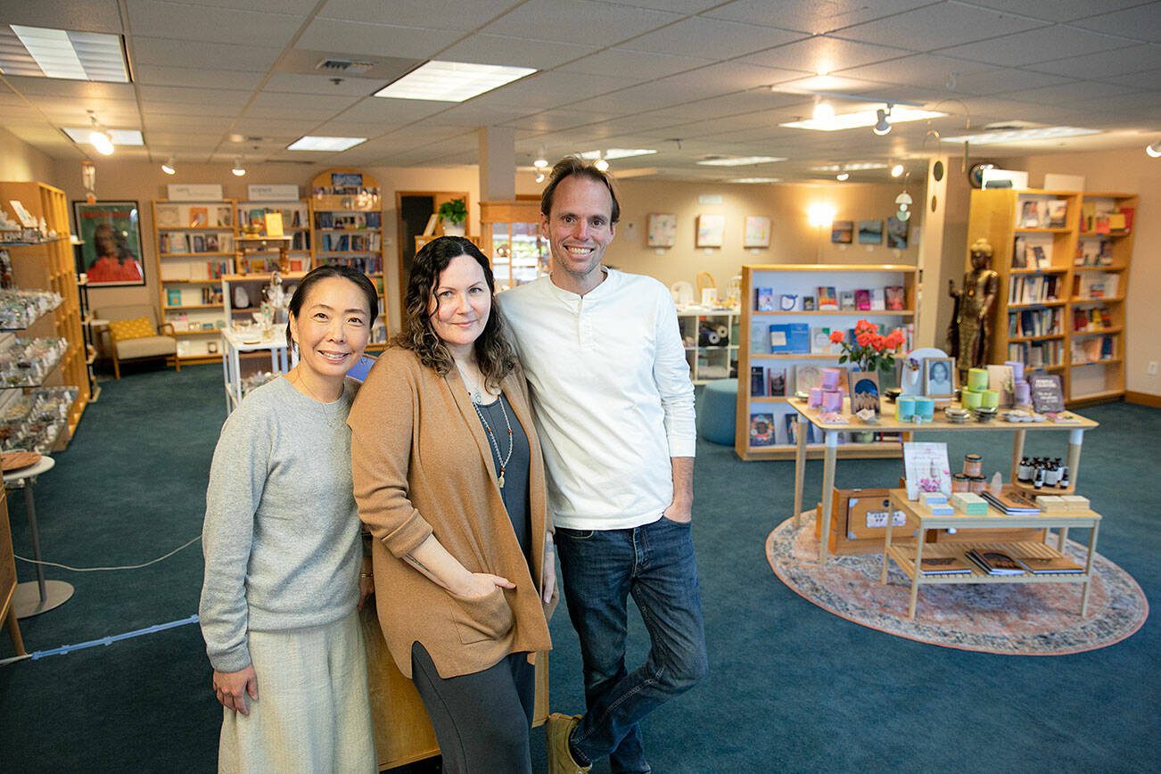 Manager Rika Rafael, left, visual merchandiser April Votolato, center, and assistant manager and events coordinator Jaidhara Sleighter stand at the entrance of East West Books & Gifts’ new location Friday, Oct. 27, 2023, in downtown Edmonds, Washington. (Ryan Berry / The Herald)