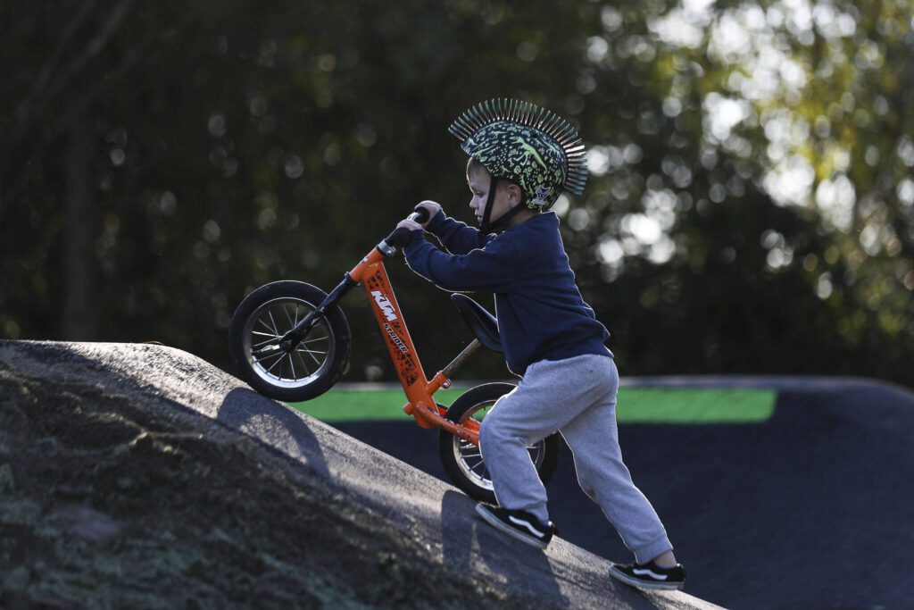 Rory Dunn, 4, pushes his bike on a new pump track at Jennings Nature Park in Marysville. (Annie Barker / The Herald)
