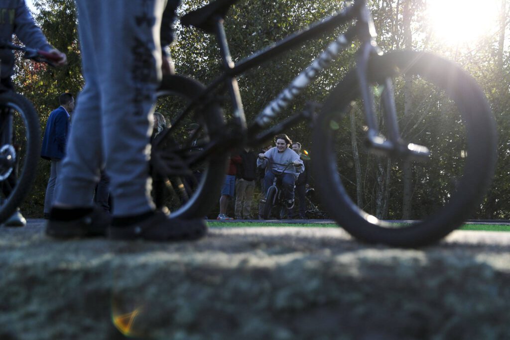 Kids, teens and adults try out a new pump track for bikes at Jennings Nature Park in Marysville. (Annie Barker / The Herald)
