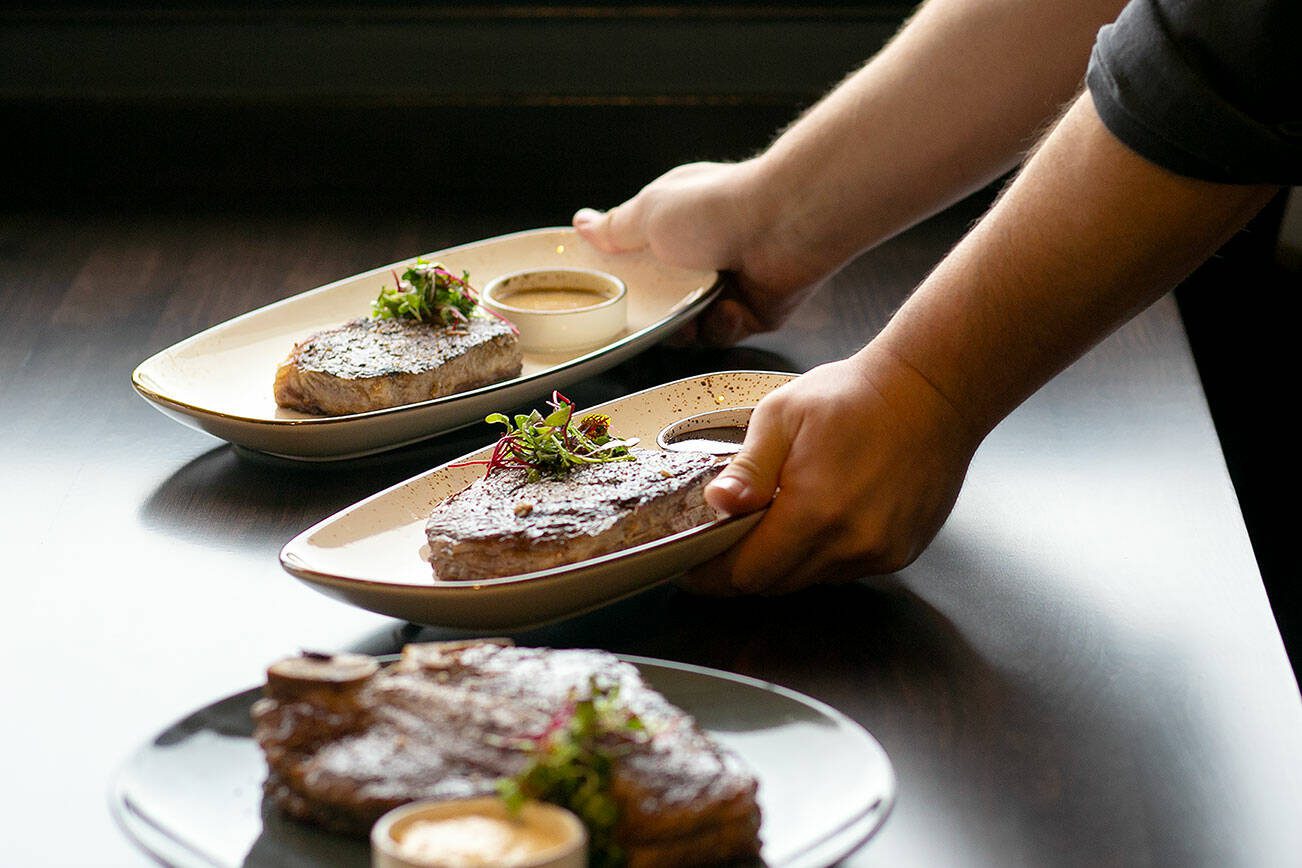 Chef Andy Hilliard delivers three different cuts of steak for staff to taste as they prepare to open Hook & Cleaver on Wednesday, Nov. 1, 2023, in Mukilteo, Washington. (Ryan Berry / The Herald)