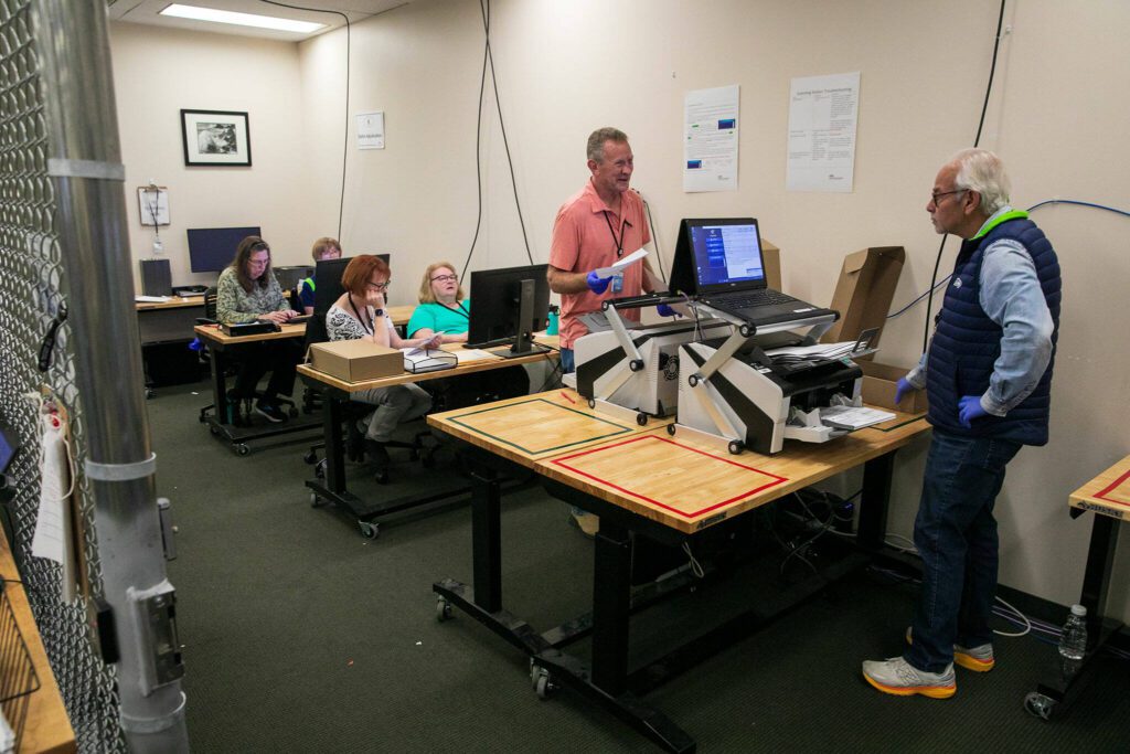 Election workers run ballots through tabulators at the Snohomish County Auditor’s office on Friday, Nov. 3, 2023, in downtown Everett, Washington. (Ryan Berry / The Herald)
