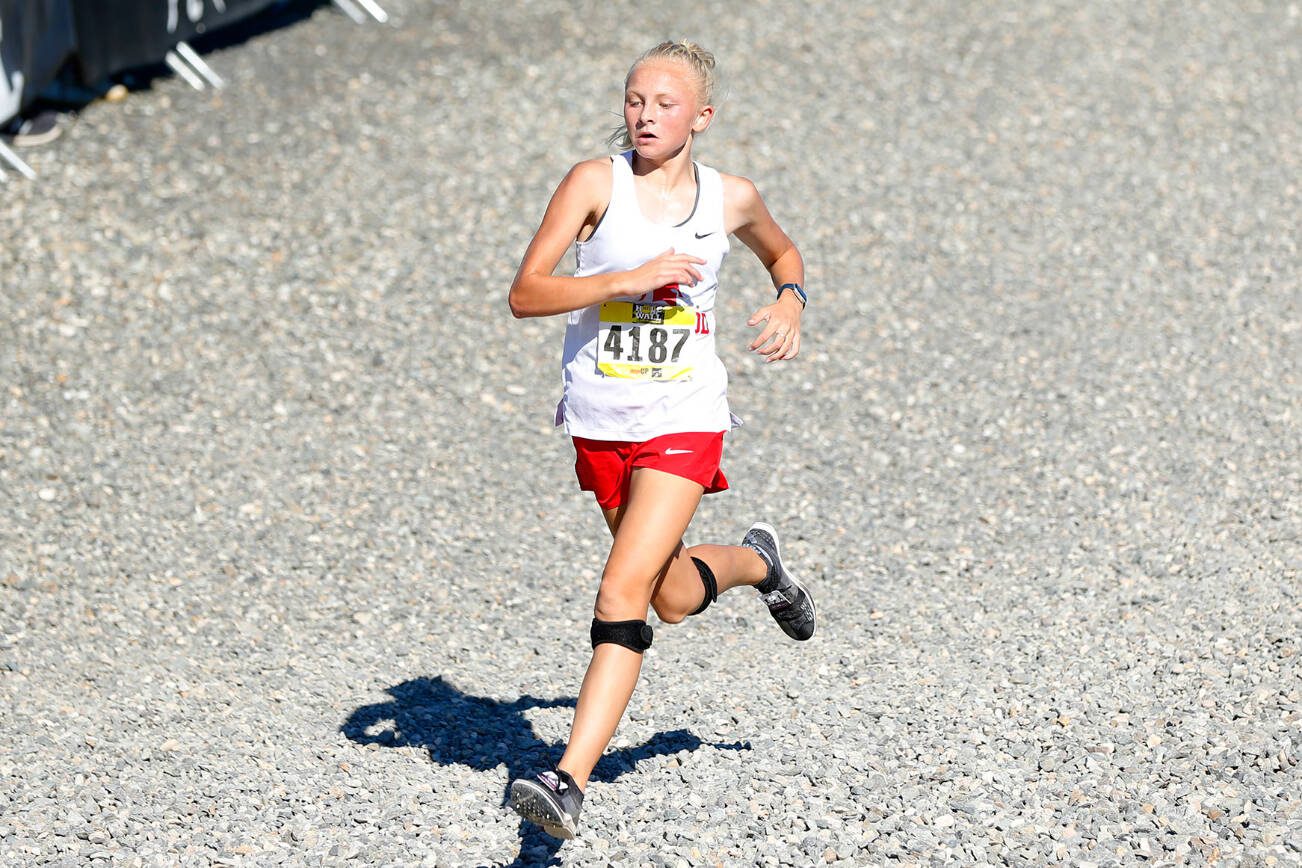 Stanwood runner Mary Andelin enters the final stretch while she cruises to a first place finish in the Women’s Varsity Gold run during the Hole in the Wall Cross Country Invitational on Saturday, Oct. 7, 2023, at Lakewood High School in Arlington, Washington. (Ryan Berry / The Herald)